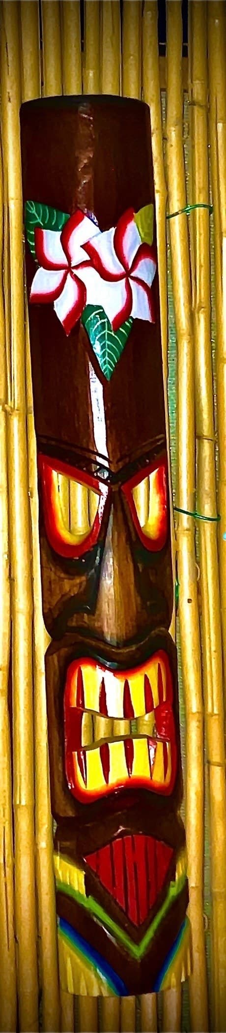 Hand-carved tiki mask on bamboo backdrop
